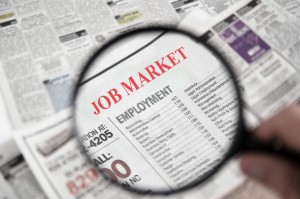 Magnifying glass over a newspaper classified section with Job Market text